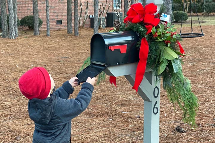 child looking inside mailbox with christmas decorations
